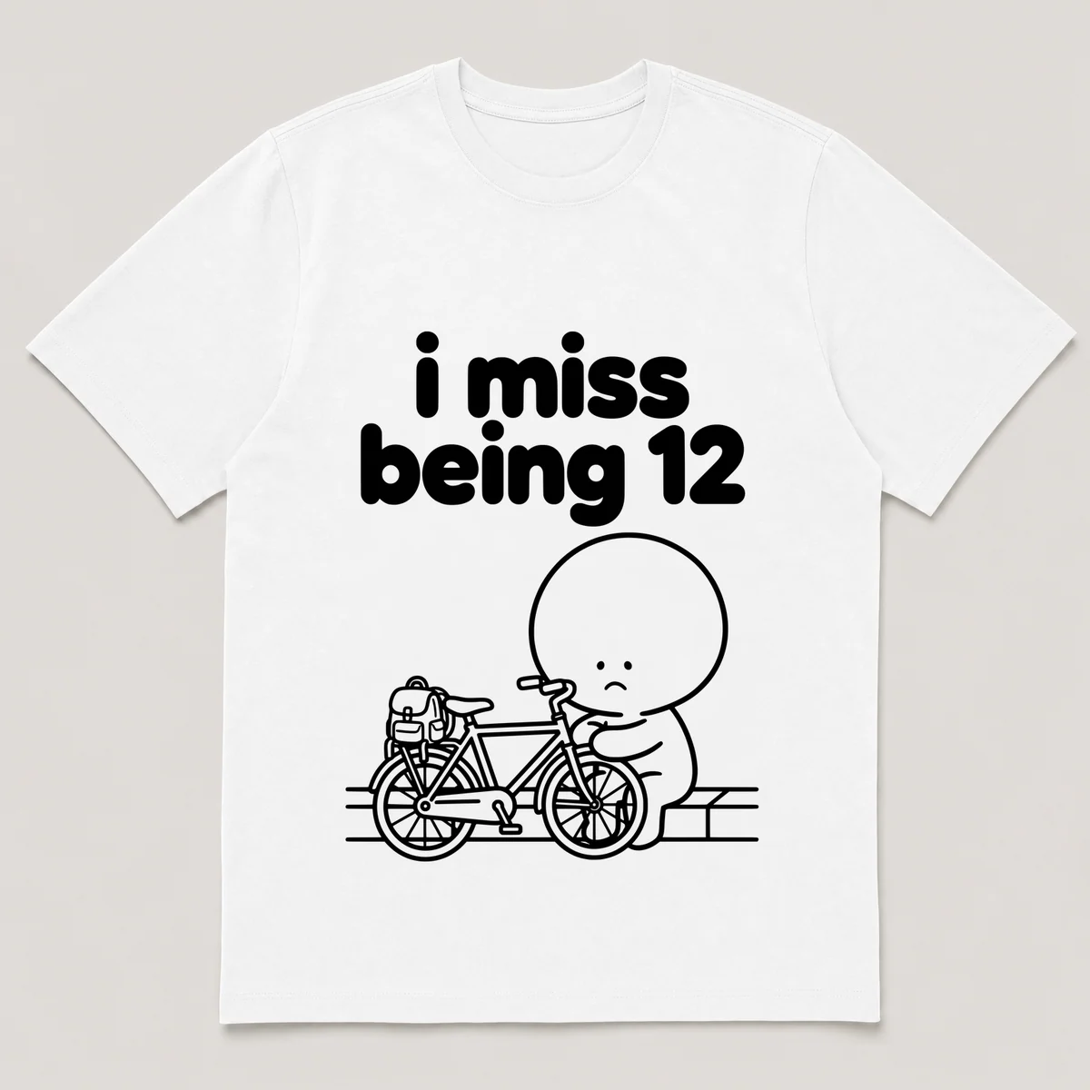 lonely boi tee: a small sad cartoon boy hugging a bike with a backpack by a curb, with the words i miss being 12 above him, White front view