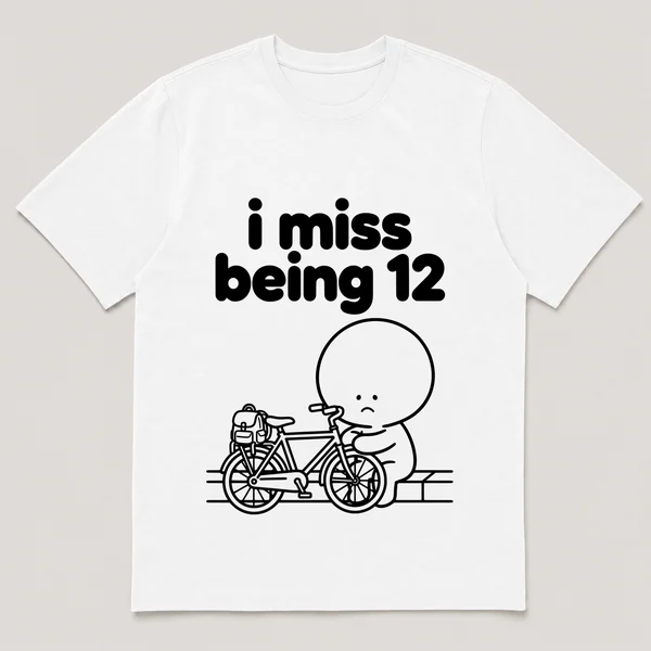 lonely boi tee: a small sad cartoon boy hugging a bike with a backpack by a curb, with the words i miss being 12 above him