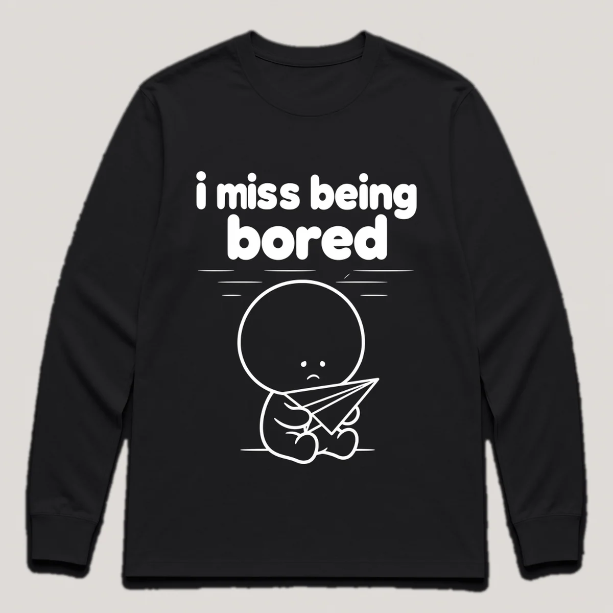lonely boi tee: a small sad cartoon boy hugging a paper airplane drifting across a ceiling, with the words i miss being bored above him, Black front view