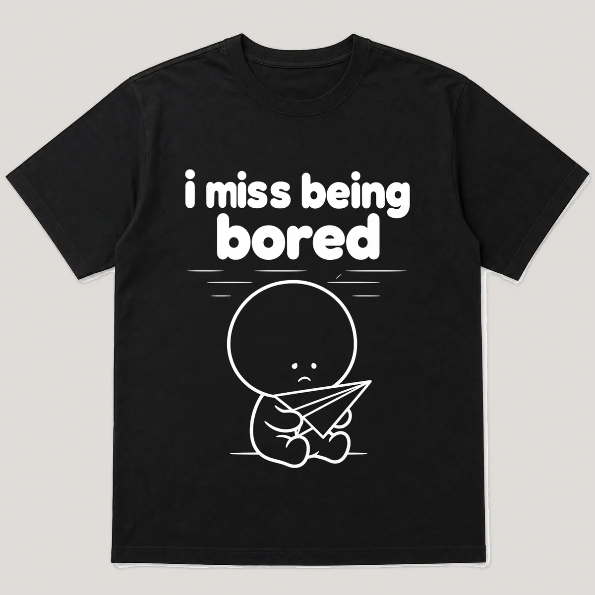 lonely boi tee: a small sad cartoon boy hugging a paper airplane drifting across a ceiling, with the words i miss being bored above him, Black front view