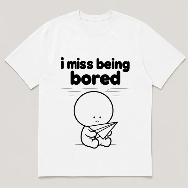 lonely boi tee: a small sad cartoon boy hugging a paper airplane drifting across a ceiling, with the words i miss being bored above him