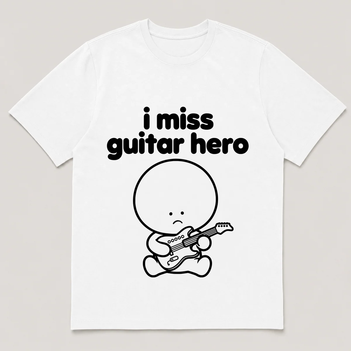 lonely boi tee: a small sad cartoon boy hugging a small plastic guitar controller, with the words i miss guitar hero above him, White front view