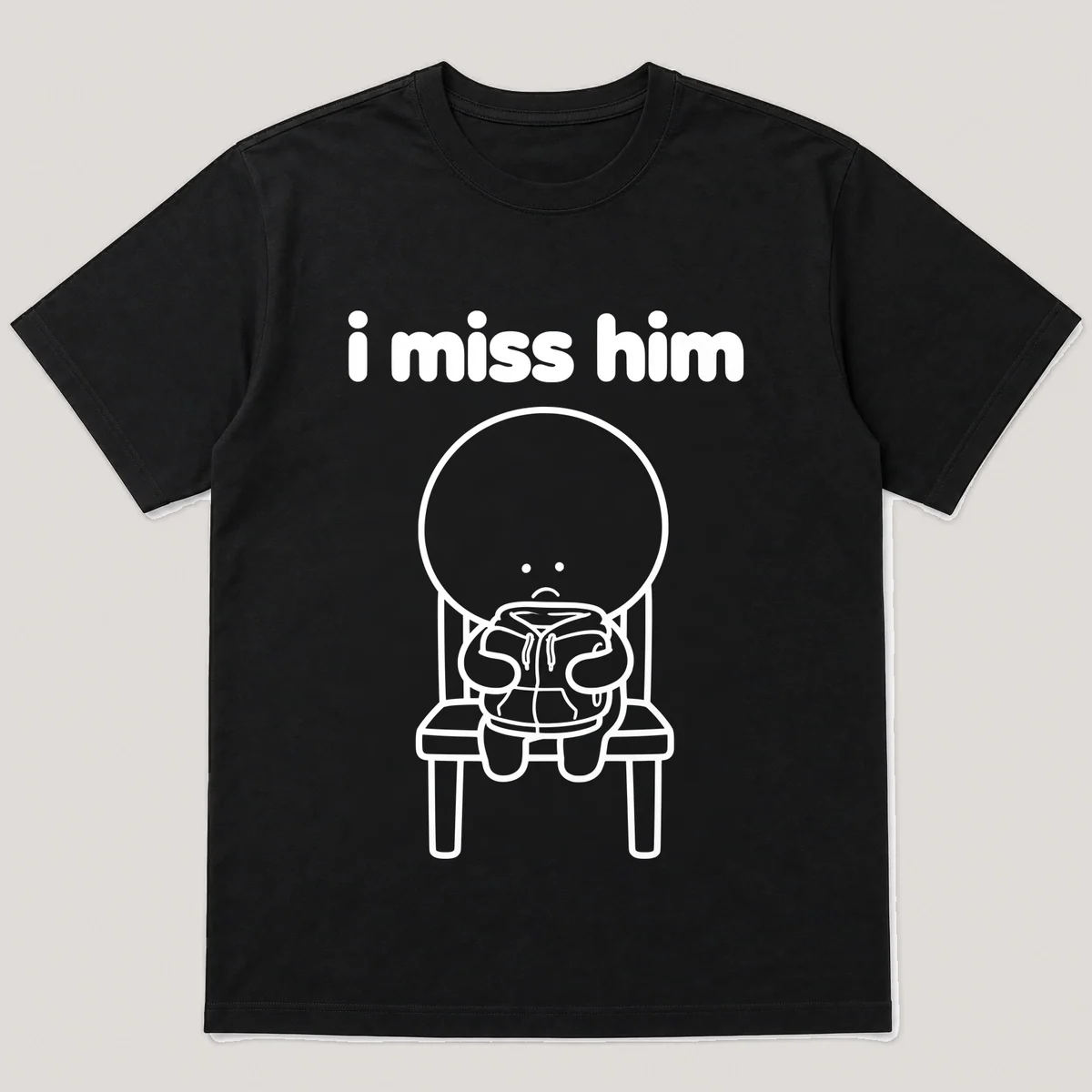 lonely boi tee: a small sad cartoon boy hugging a folded hoodie left on a chair, with the words i miss him above him, Black front view