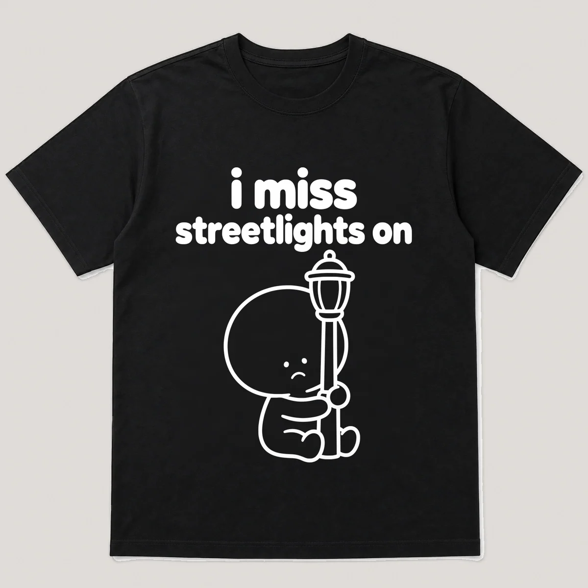 lonely boi tee: a small sad cartoon boy hugging a glowing streetlight at dusk, with the words i miss streetlights on above him, Black front view