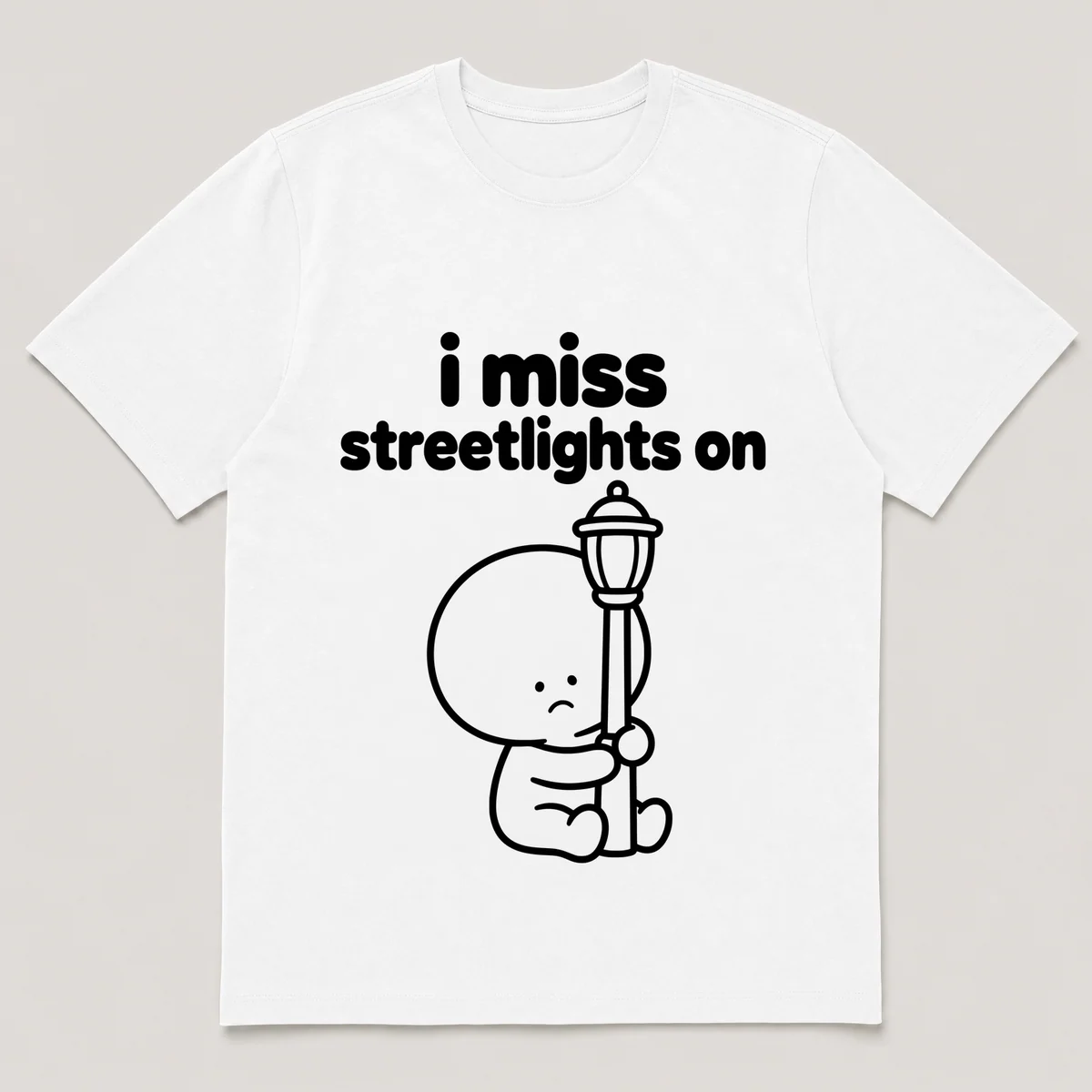 lonely boi tee: a small sad cartoon boy hugging a glowing streetlight at dusk, with the words i miss streetlights on above him, White front view