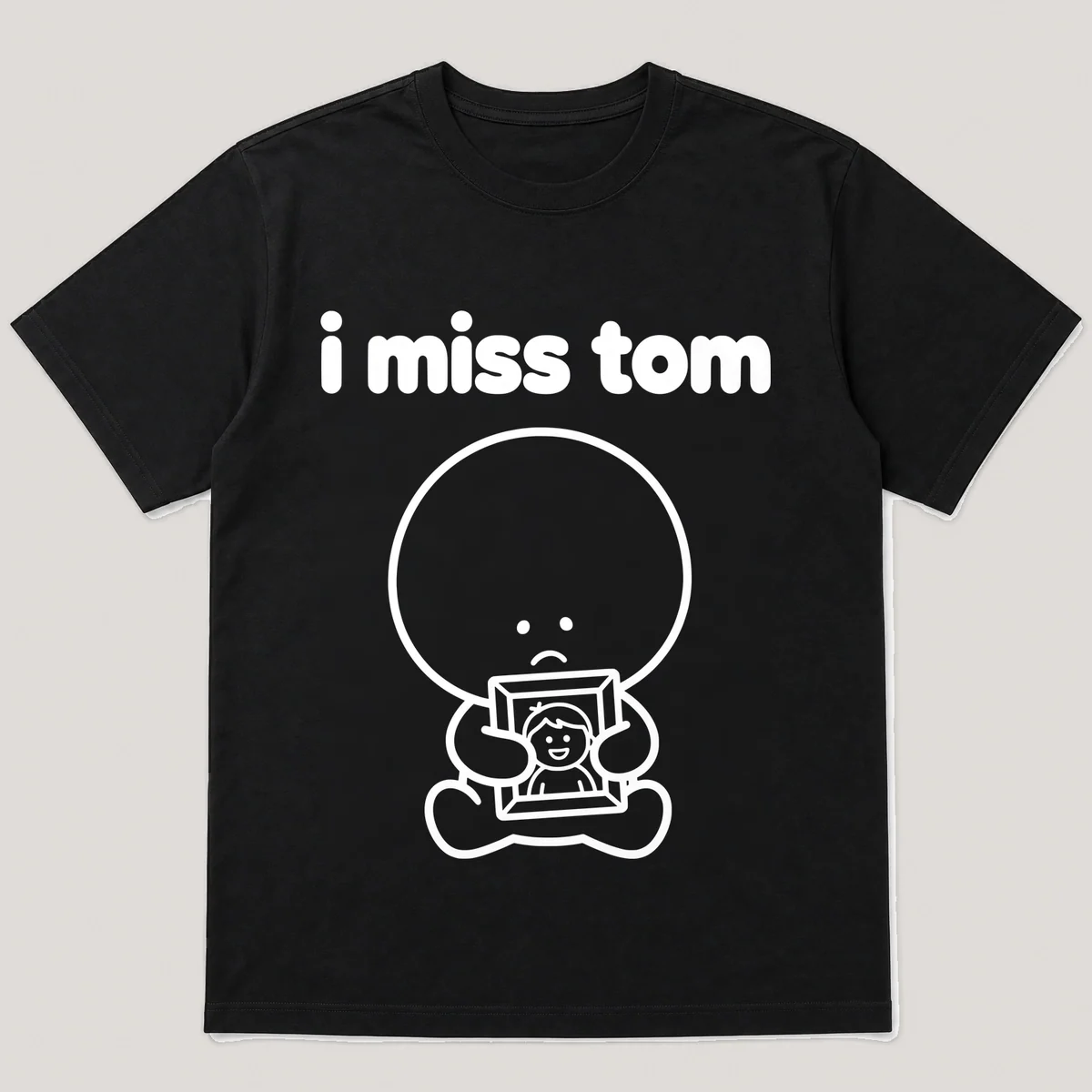 lonely boi tee: a small sad cartoon boy hugging a framed photo of a smiling friend, with the words i miss tom above him, Black front view