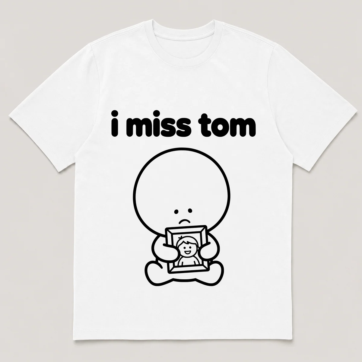 lonely boi tee: a small sad cartoon boy hugging a framed photo of a smiling friend, with the words i miss tom above him, White front view